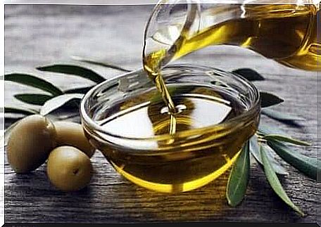 Olive oil in a bottle is poured into a bowl