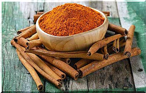 Bowl of ground cinnamon on a wooden table with cinnamon sticks