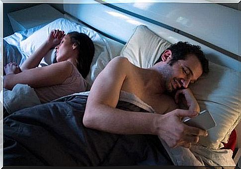 Couple in bed ignoring each other