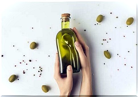 Olive oil in a bottle with olives around it