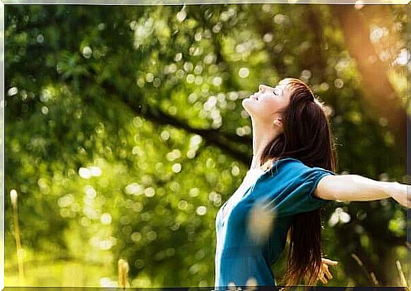 Woman with outstretched arms in the woods