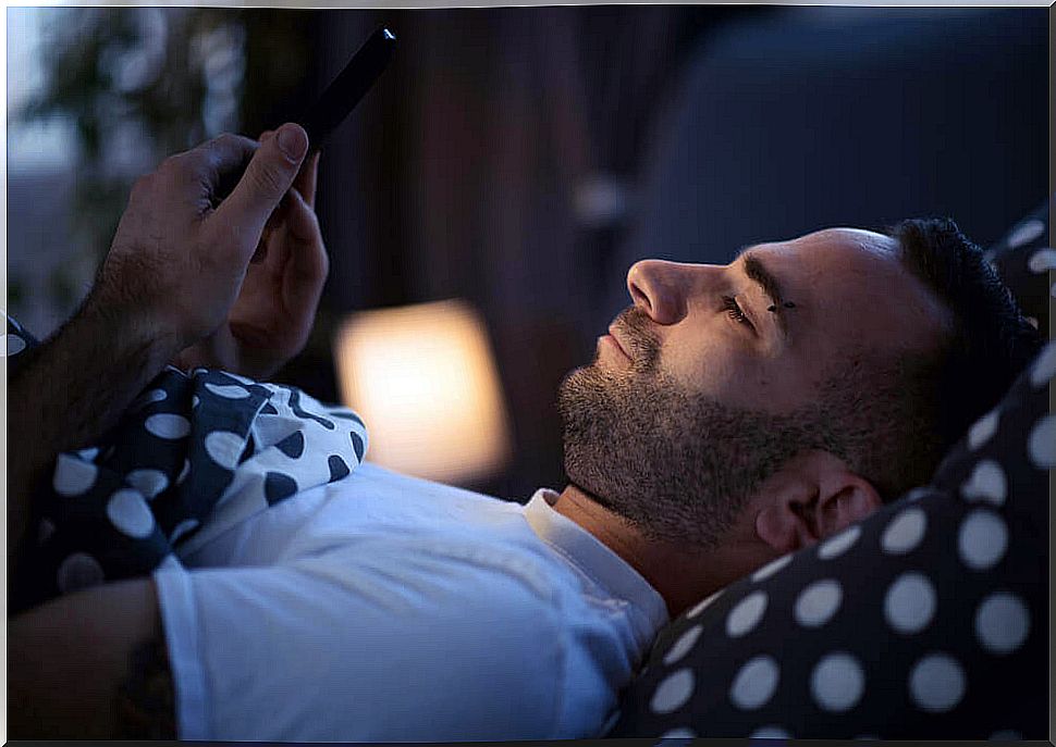 Man with smartphone in bed suffers from nomophobia