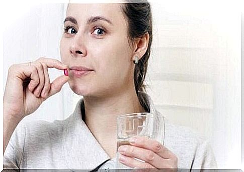 A woman holds a pill to her mouth